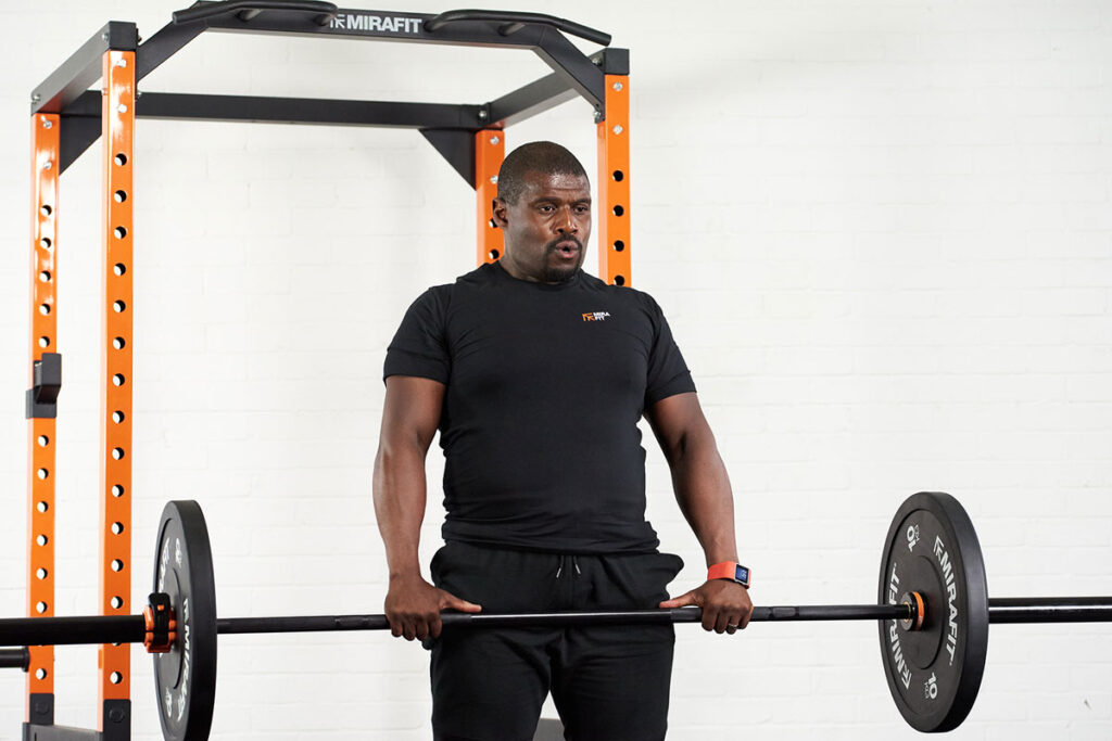 Man deadlifting Mirafit weights in front of a Mirafit Power Rack